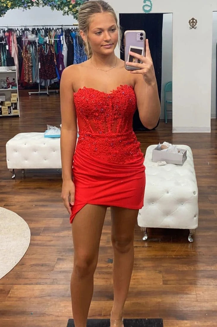 A woman takes a mirror selfie in a boutique wearing a bright red strapless sweetheart mini dress with a beaded bodice and ruched skirt. 