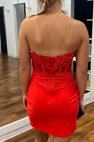 A woman takes a mirror selfie in a boutique wearing a bright red strapless sweetheart mini dress with a beaded bodice and ruched skirt. 