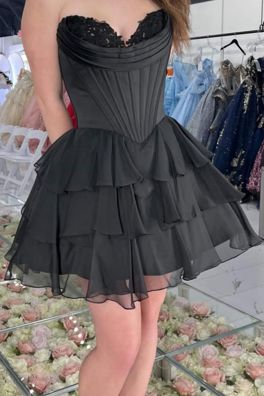 Black dress with ruffled layers worn by a person in a store setting.