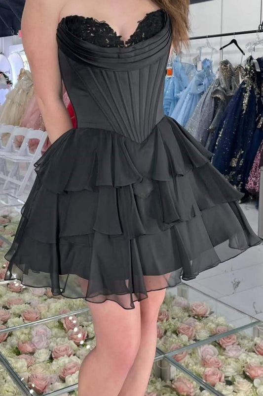 Black dress with ruffled layers worn by a person in a store setting.