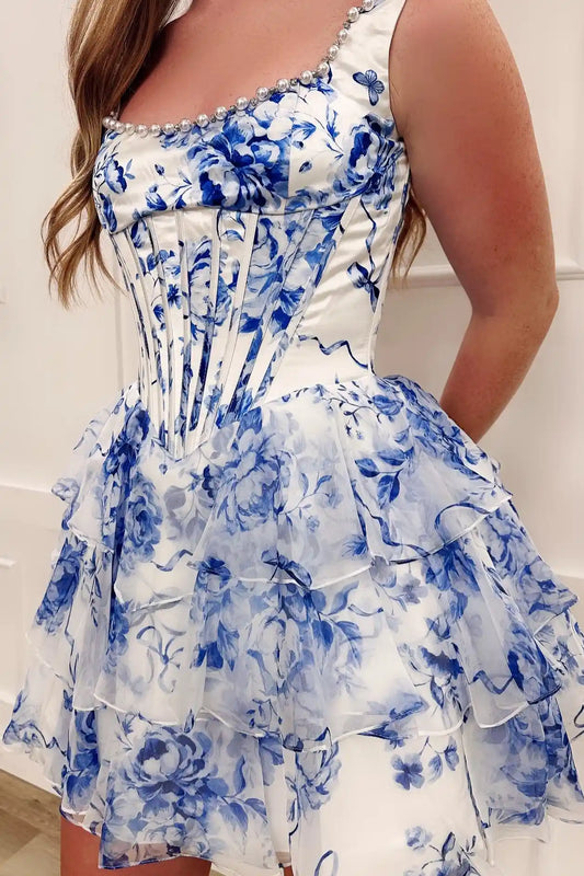 A sleeveless homecoming short dress with a blue floral print, featuring a structured corset-style bodice and a tiered ruffled skirt.