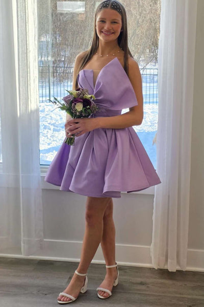 Woman wearing a bright pink dress with a large bow in an outdoor setting.