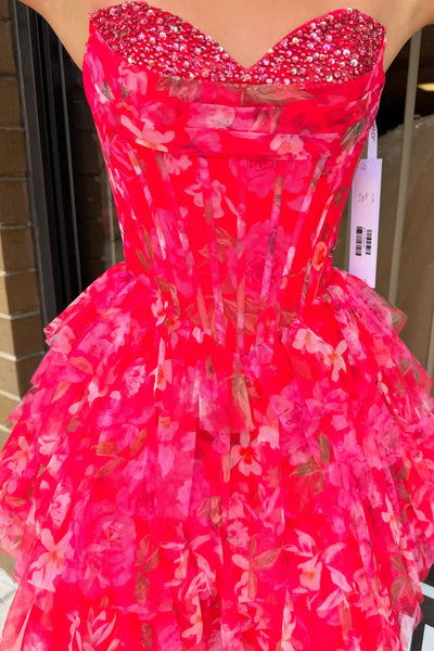 A woman wearing a fuchsia strapless tulle dress with a floral pattern and beaded sweetheart neckline, posing in front of a storefront window.
