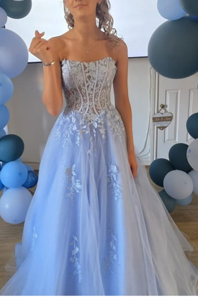 A woman wearing a strapless blue tulle ball gown with a beaded corset bodice.