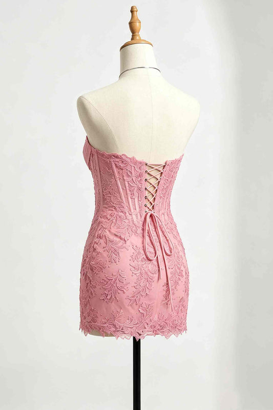 A pink lace strapless homecoming dress displayed on a cream dress form mannequin, showing the lace-up back detail.