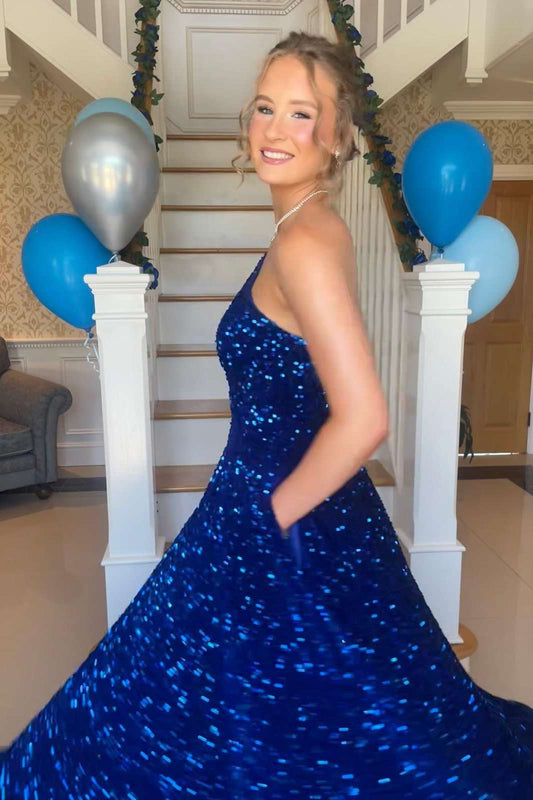 A woman wearing a sparkling royal blue strapless gown with a full skirt, standing in a decorated indoor staircase area with blue and silver balloons.
