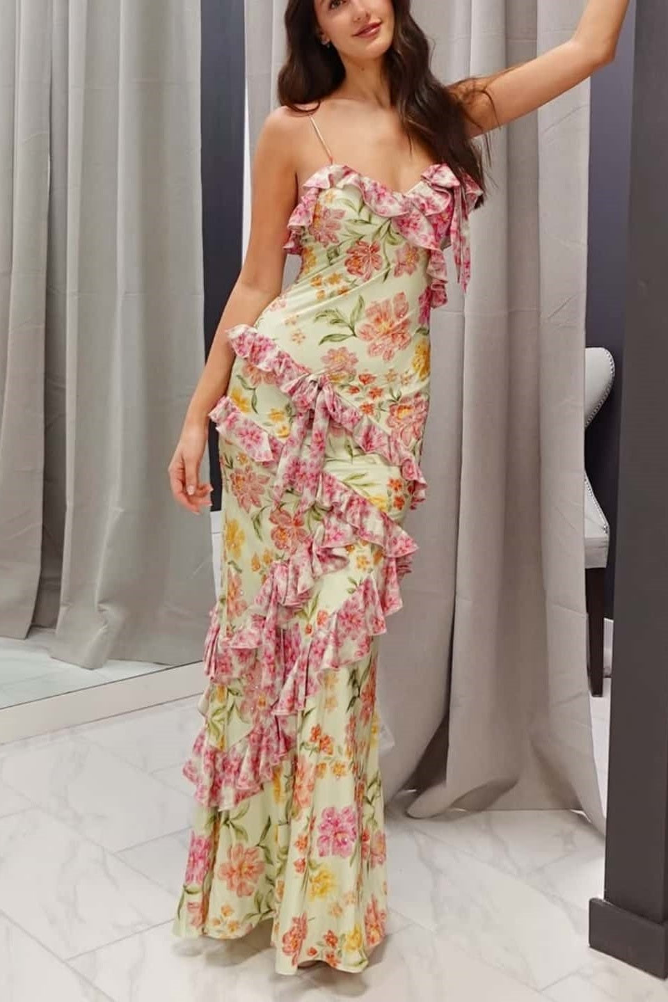 Woman wearing a floral dress standing against a neutral background
