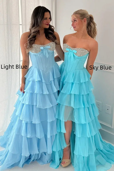 Woman wearing a mint green strapless dress with ruffled layers in a room.