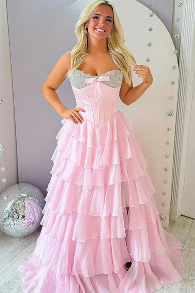 Woman wearing a mint green strapless dress with ruffled layers in a room.