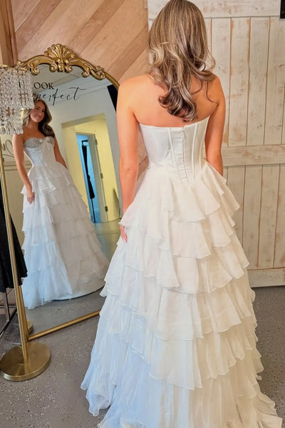 Woman wearing a mint green strapless dress with ruffled layers in a room.