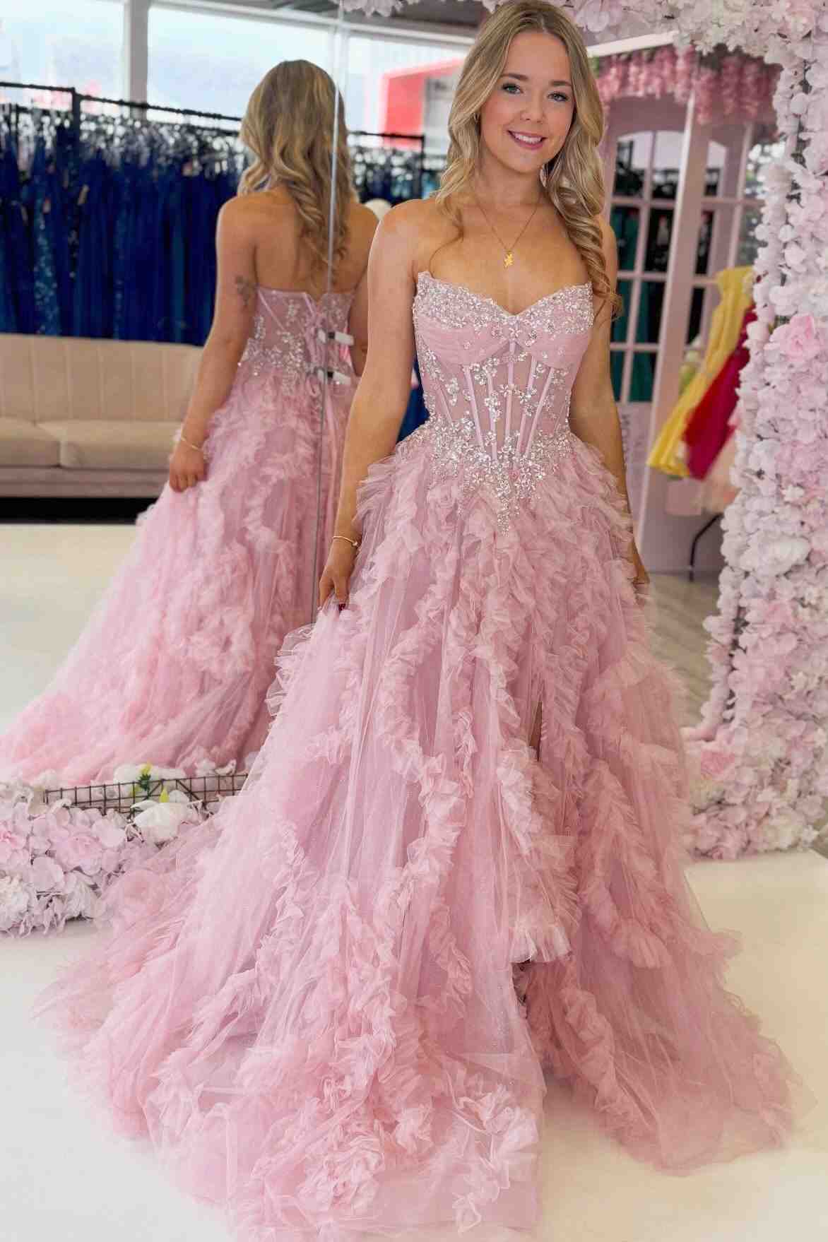 A woman wearing a strapless pink ball gown with a beaded corset bodice and layered tulle skirt.