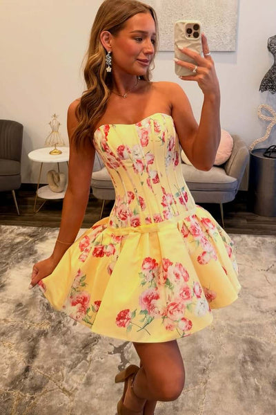 Woman taking a mirror selfie wearing a yellow floral dress in a room.
