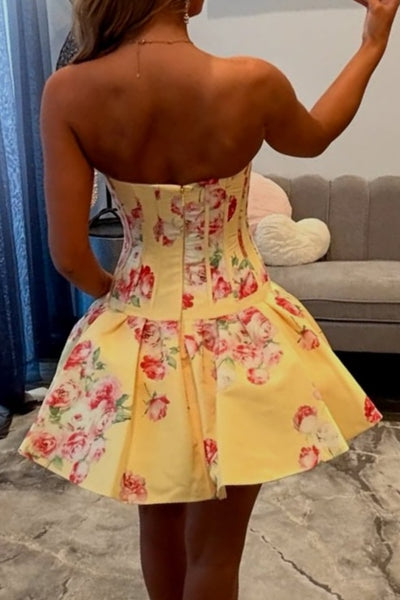 Woman taking a mirror selfie wearing a yellow floral dress in a room.