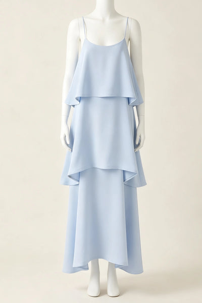 A pale yellow tiered maxi bridesmaid dress with spaghetti straps, displayed on a white mannequin against a solid beige background.