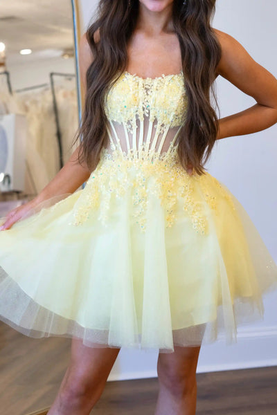 Yellow strapless corset lace applique tulle mini dress on a woman in a bridal studio